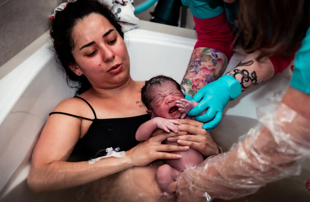 A woman gently cradles a baby in a bathtub, creating a warm and loving moment between them.